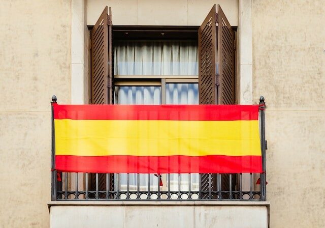 A Spanish flag hung over an apartment balcony. 