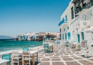 A beach front restaurant with tables outside over looking the ocean. 