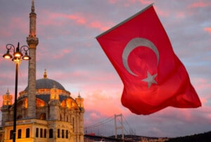 Turkish flag waving in front of historical building representing immigration to Turkey