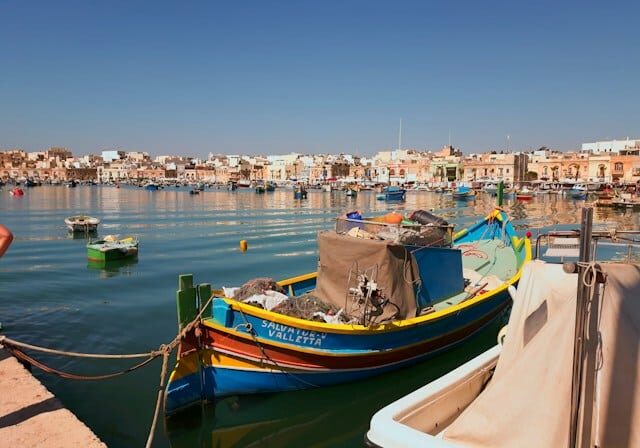 Colorful boats by the shore with buildings in the background. 