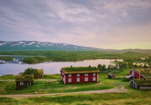 Red house in the countryside of Sweden against a pink sky and mountains - least corrupt countries