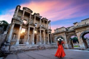 Woman in red dress exploring the ancient Library of Celsus in Ephesus, Turkey at sunset