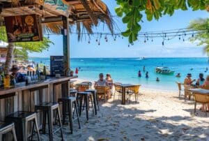 Beach bar in Caribbean with people sitting on chairs in the sand - Caribbean Citizenship by Investment programs