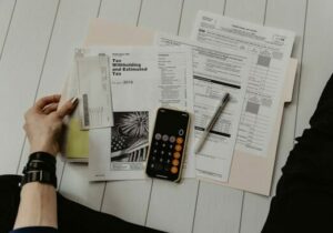Person filing taxes and using a calculator on a wooden floor - International expat insurance costs