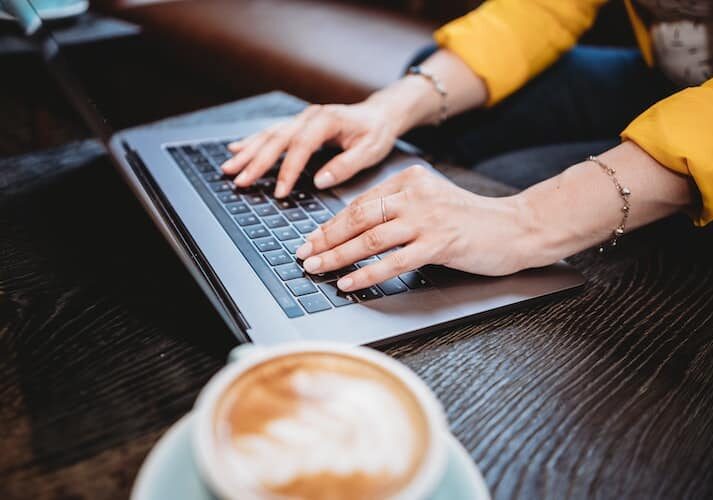 Person typing on a laptop with a cup of coffee next to them - Digital nomad visas for European countries