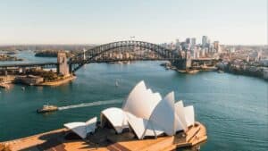 Aerial view of Sydney Opera House and the South Pacific Ocean with boats racing by and a bridge in the background - 10th least corrupt countries