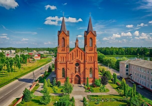 View of Saints Simon and Helena church in Belarus surrounded by green trees - using cryptocurrency in Europe