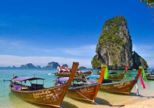 Colorful boats moored on the shoreline of a beach in Thailand - Americans are moving to Thailand