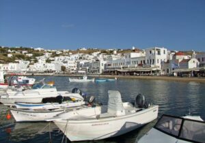 White houses overlooking the water with boats floating nearby.