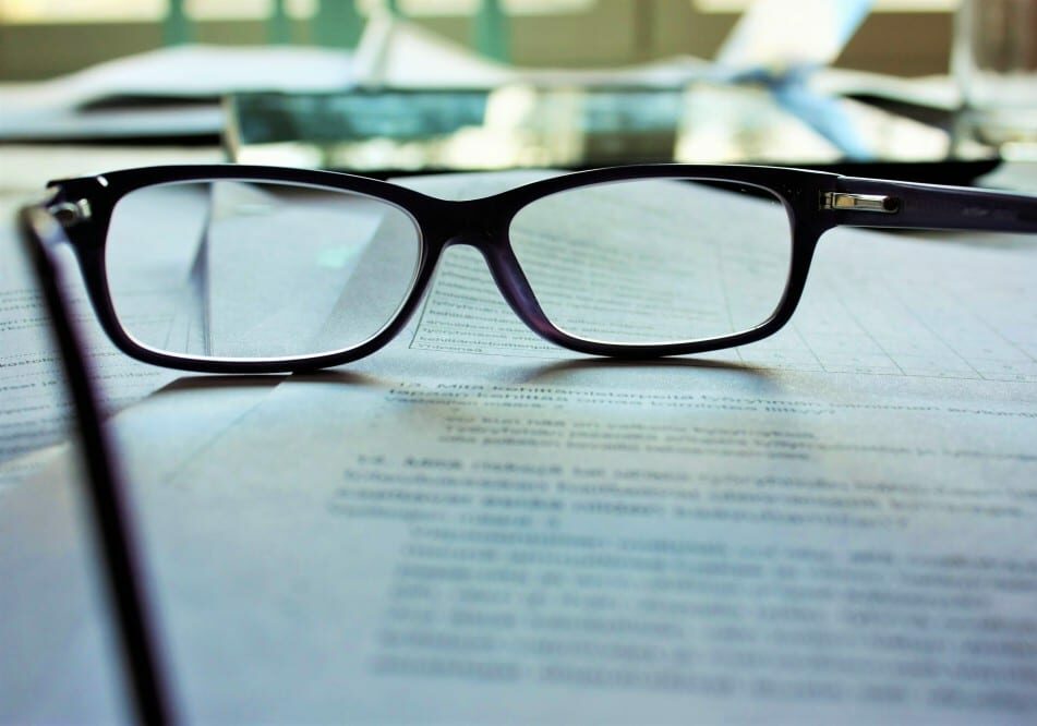 A pair of glasses on a pile of papers.
