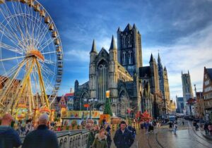 Saint Nicholas Church on Korenmarkt Wheat Market square, Belfry Het Belfort van Gent and row of colorful buildings in Belgium - English-speaking countries for expats