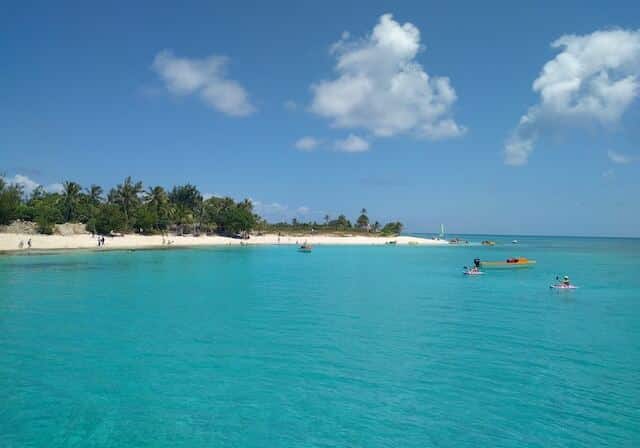 People and boats relaxing in bright blue water surrounding Vanuatu - countries with no income tax
