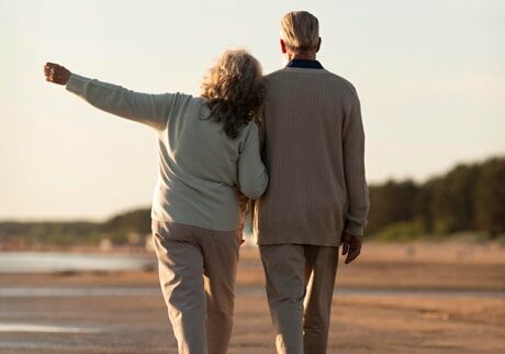 Older couple walking arm in arm on a beach - Best Places to Retire in the World