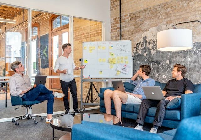 People sitting in an office having a meeting in front of a whiteboard - Portugal D2 Visa