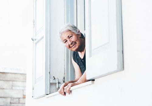 An elderly woman looking out a window. 