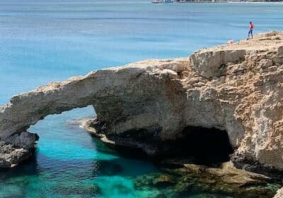 Man standing on a beach cliff's edge in Paphos, Cyprus - beach towns for retirement