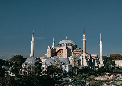 Exterior view of Hagia Sophia in Istanbul, Turkey, showcasing its massive dome and four minarets under a clear blue sky.