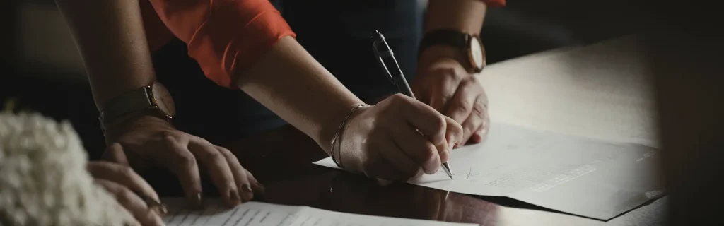 person signing documents with a lawyer