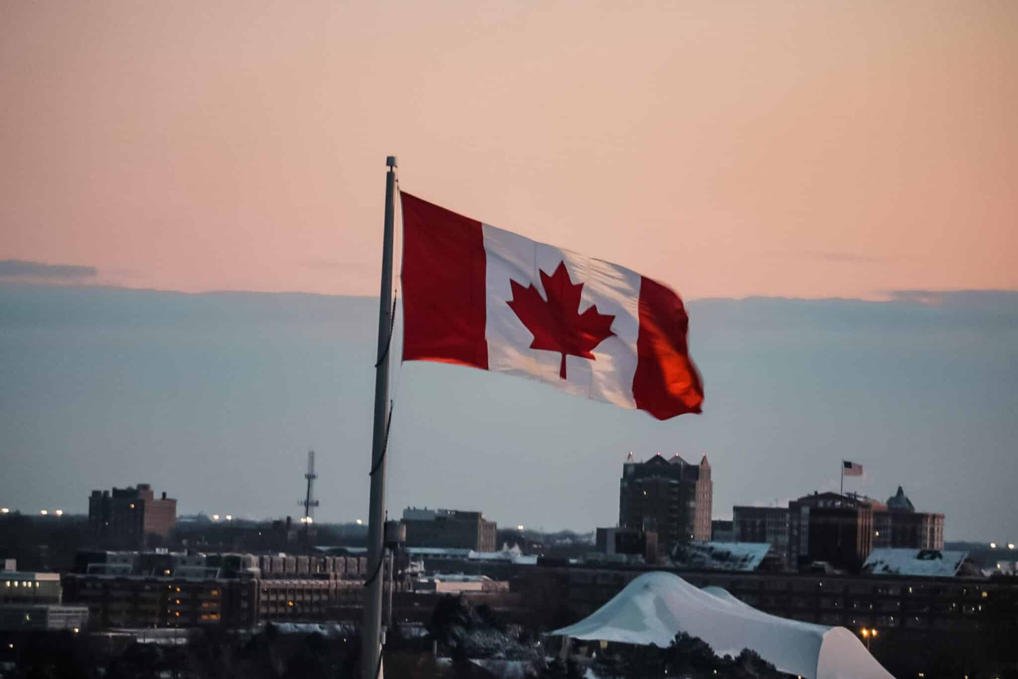 a view of the canadian flag waving in dusk