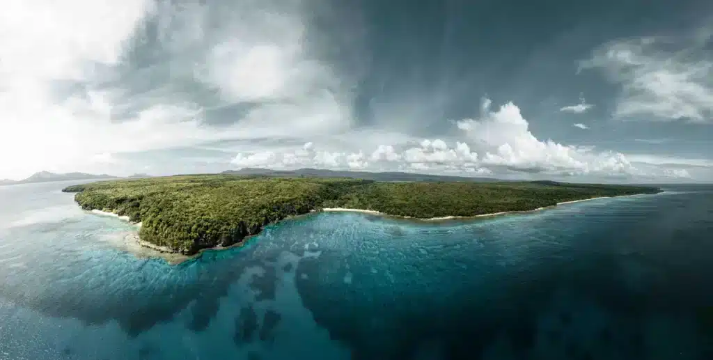 Aerial view of a tropical island featuring pristine white sand beaches and clear blue waters surrounding the land.