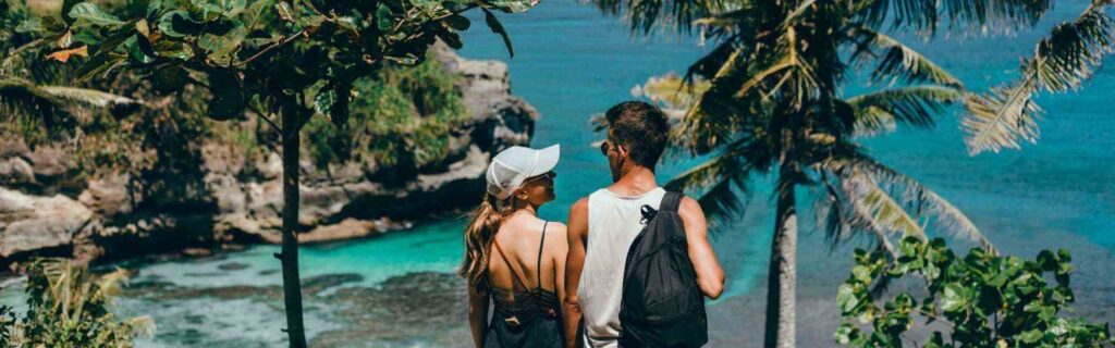 two travelers facing in a tropical settiing facing the ocean