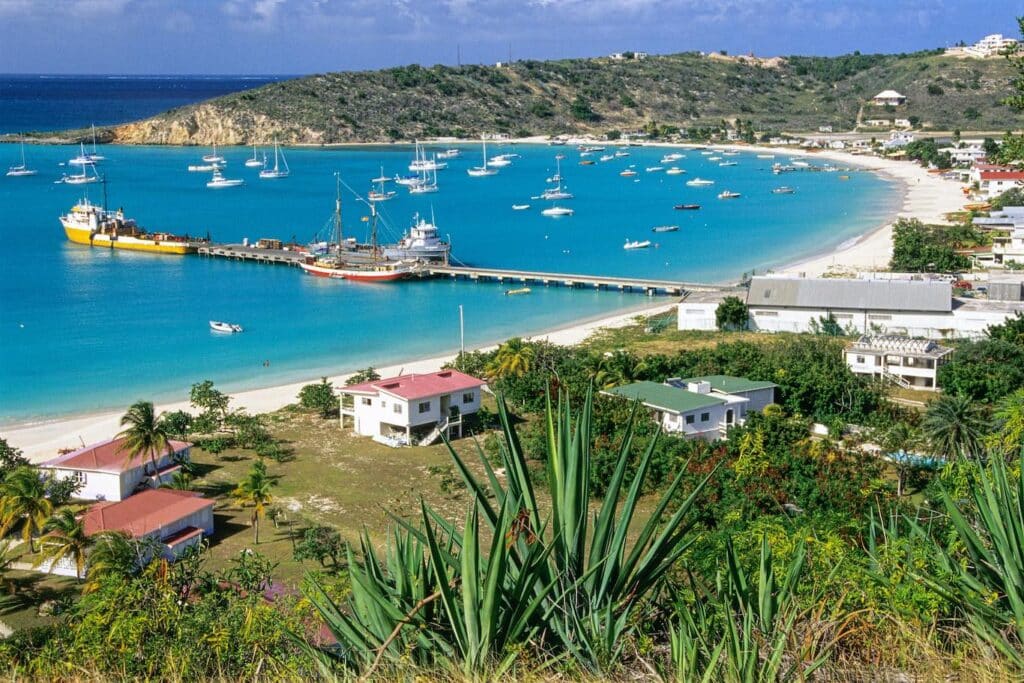 A scenic beach view with several boats docked along the sandy shore under a clear blue sky.