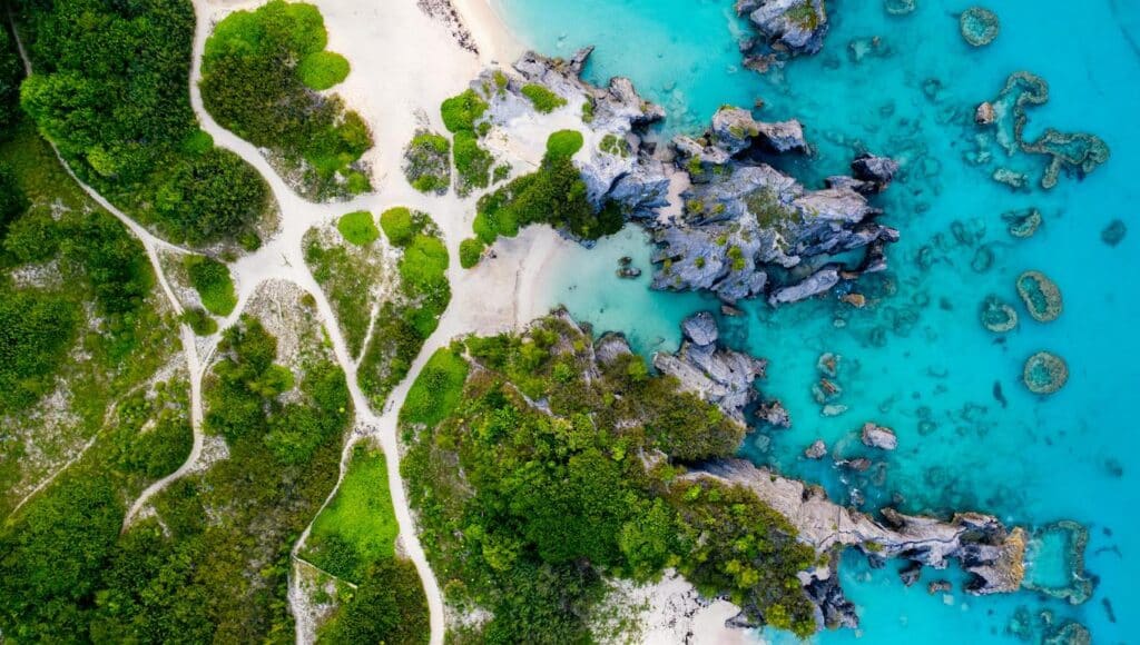 Aerial view of a sandy beach with turquoise water, showcasing the coastline and gentle waves lapping at the shore.