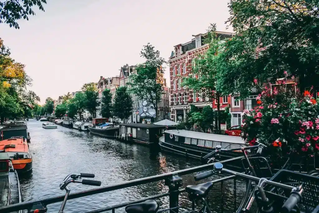 A scenic view of Amsterdam's iconic canals lined with historic buildings and boats under a clear blue sky - best digital nomad countries