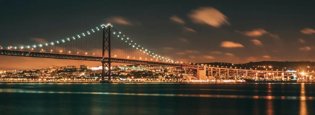 view of lisbon with the tagus river and the 25 de abril bridge by night