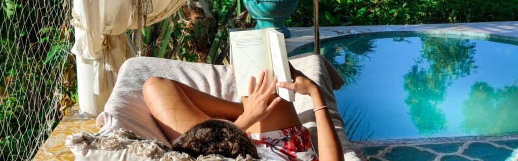 a hotel guest reading on an outdoor bed at White Grass Ocean Resort & Spa